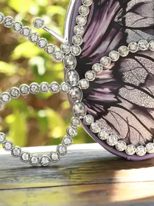 Gros plan d'un sac de soirée papillon avec contour en strass et imprimé violet élégant