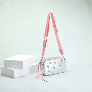 Detalle del bolso cámara plateado con pedrería multicolor y correa rosa de moda