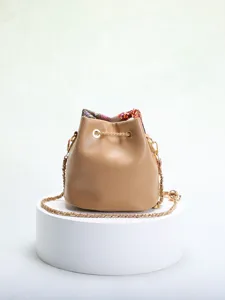 Elegant bucket bag with floral embroidery and sequin mesh detail on a white pedestal.