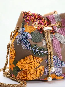 Detail view showing colorful flower embroidery and shiny sequins on a mesh bucket bag