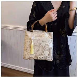 Elegant detail view of floral embroidery and bamboo handle on a luxury evening handbag.