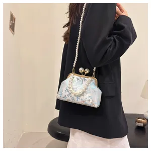 Elegante pochette ricamata con tracolla di perle indossata da una modella.