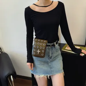 Detail of dark style brown waist bag with metal eyelets and cross motif worn on a denim skirt.