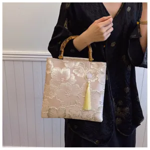 Elegant floral embroidered handbag with vintage bamboo handle and decorative tassel.