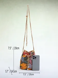 Detailed view of floral embroidered bucket bag showing size with measurements and phone