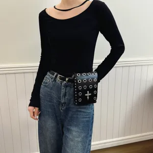Detail view of a dark punk style waist bag featuring metal eyelets and a skull cross charm