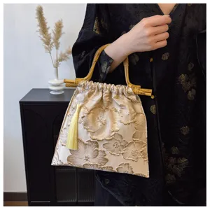 Detail shot of an embroidered linen handbag with bamboo handles and a yellow tassel.