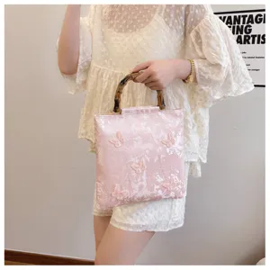 Lifestyle view of the pink embroidered handbag featuring an authentic natural bamboo handle