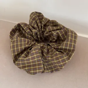 Detailed view of an oversized plaid scrunchie with retro purple and green checks.