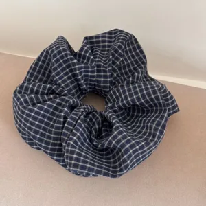 Close-up detail of a navy blue and white checkered fabric scrunchie hair tie accessory.