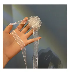 Macro view of a white lace hair ribbon featuring a delicate sheer flower ornament.