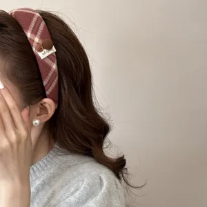Detailed close-up of a stylish retro red plaid headband with decorative button on model