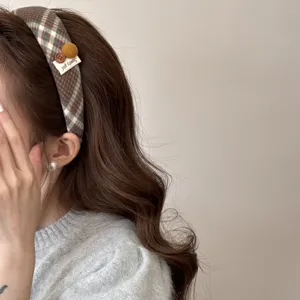 Close-up of retro plaid headband with decorative buttons and Sweety girl tag