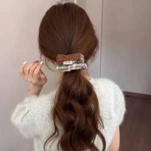 Close-up showing a vintage plaid bow hair scrunchie styled on a brunette ponytail