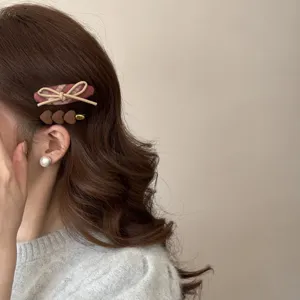 Close-up of retro plaid bow and heart-shaped hair clips on brunette hair.