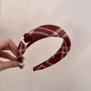 Detail view of retro red plaid fabric and decorative label on the elegant padded headband.
