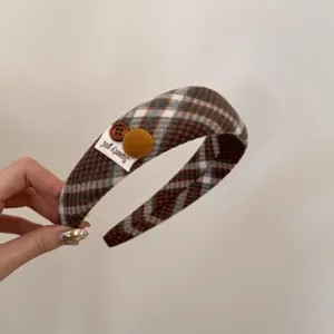 Close-up detail of retro plaid headband featuring buttons and a 'Sweety girl' fabric tag