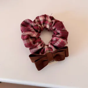Close-up detail of retro red plaid scrunchie featuring a dark brown ribbon bow accent