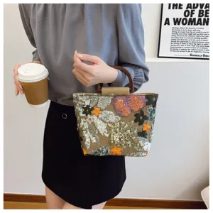 Dettaglio borsa vintage in lino con paillettes floreali e manico in legno
