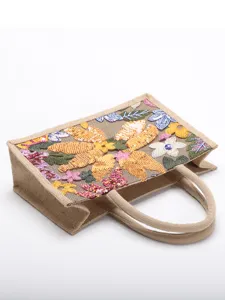 Detailed macro view of colorful floral sequin embroidery on a woven jute tote bag
