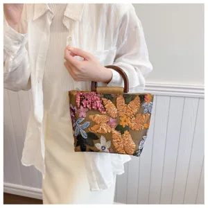 Dettaglio di elegante borsa tote in lino con ricamo di fiori di paillettes e manico in legno