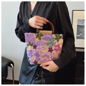 Elegante borsa in lino con paillettes floreali e manici in legno portata dal modello