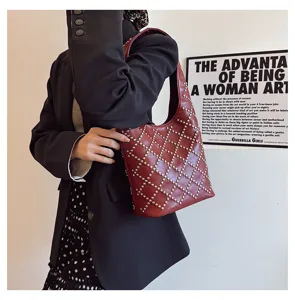 Close-up of a red punk-style studded bucket bag worn by a model in a blazer.