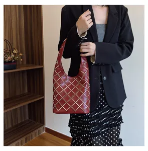 Chic red shoulder hobo bag featuring silver rivet studs in a diamond pattern on model
