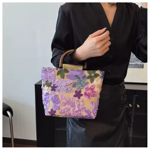 Dettaglio borsa in lino con ricamo floreale di paillettes viola e manico in legno