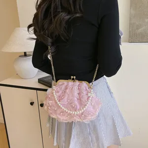 Détail d'un élégant sac pochette rose à pétales avec perles et bandoulière en chaîne
