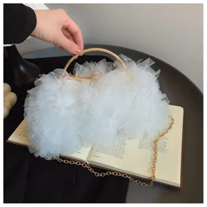 Detailed close-up of a white lace ruffled evening clutch bag featuring a gold-tone handle