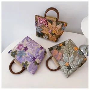 Vista dettagliata di tre eleganti borse in lino con paillettes floreali e manici circolari