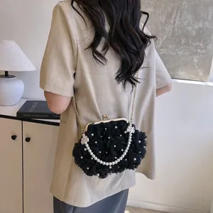 Vue de dos d'une femme portant un sac bandoulière noir à fleurs avec perles et chaîne dorée