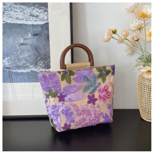 Dettaglio della borsa in lino con ricamo di fiori in paillettes e manico rotondo