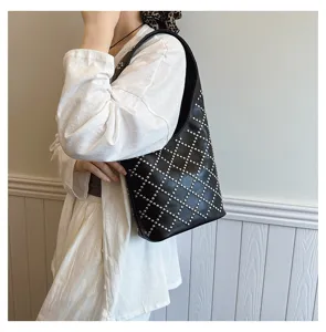 Detail of punk style black shoulder bag with silver round studs in diamond pattern