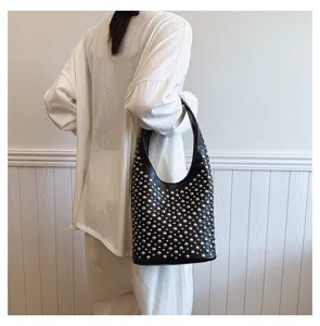 Back view of a model carrying a black punk style bucket bag decorated with silver rivets