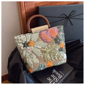 Dettaglio borsa in lino con ricami floreali di paillettes colorate e manico in legno