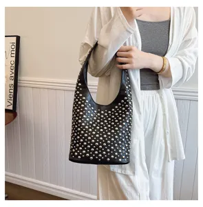Black punk style bucket bag with silver rivet studs details on a female model