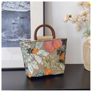 Dettaglio della borsa in lino con ricamo floreale di paillettes e manici tondi.