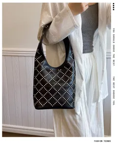 Black punk style bucket bag featuring silver round rivets carried by a model on shoulder