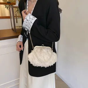 Élégant sac à bandoulière en tissu floral blanc avec perles et chaîne dorée porté par un modèle