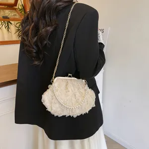Détail d'un sac sous les bras à fleurs crème avec poignée en perles et chaîne dorée