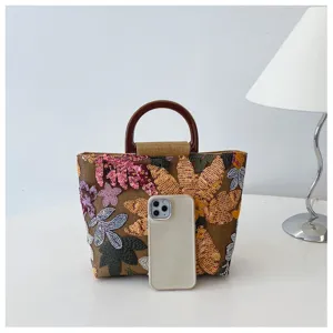 Borsa a mano in lino ricamata con fiori confrontata con uno smartphone per la taglia