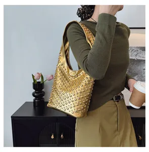 Lifestyle shot of a model carrying a gold punk style hobo bag with round rivet studs