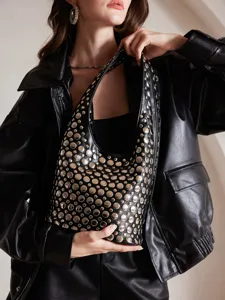 Close-up of a punk-style black leather bucket bag with silver metal studs held by a model