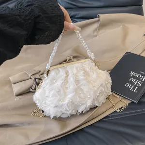 Gros plan d'un sac à main blanc à volants floraux avec perles et fermoir doré