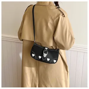 Detailed view of a black baguette bag featuring pearl heart decorations and a khaki trench coat.