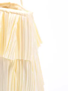Close-up detail of light yellow pleated ruffled layers on a chic lady's shoulder bag
