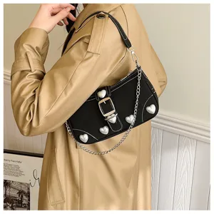 Close-up detail of a black baguette bag with silver heart studs and a metal chain strap.