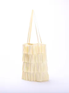 Detailed view of the delicate ruffled layers on a creamy yellow pleated fabric tote bag